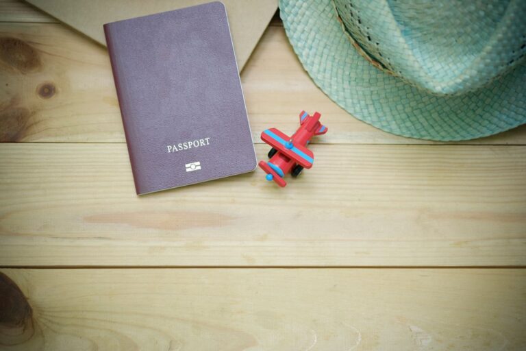 Passport, straw hat and toy airplane on a wooden surface for travel preparation
